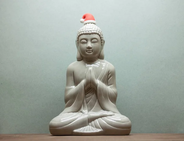 Vánoční Buddha v červené čepici santa na modrém pozadí — Stock fotografie
