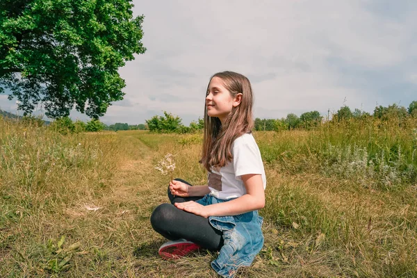 Dziewczynka Siedzi Pozycji Jogi Trawniku Relaksuje Się Tle Pięknej Wsi — Zdjęcie stockowe
