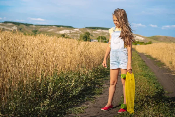 Una Adorabile Bambina Con Una Tuta Jeans Tiene Uno Skateboard — Foto Stock