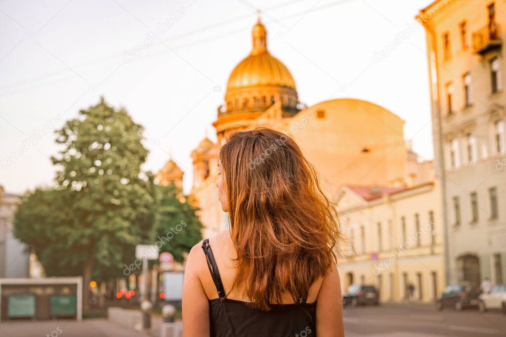 Back photo of a girl with long hair against the background of St. Isaac's Cathedral in St. Petersburg