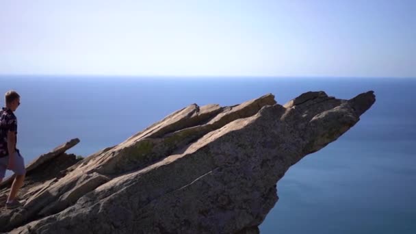 Een Jongeman Loopt Langs Een Steile Klif Uit Zee Tegen — Stockvideo