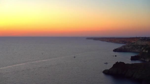 オレンジ色の夕焼け空と岩だらけの海岸 クリミア半島の岬の景色 — ストック動画