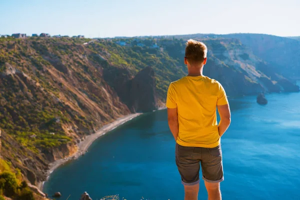 Молодой Человек Жёлтой Одежде Сидит Высоко Над Морем Фоне Прибрежных — стоковое фото