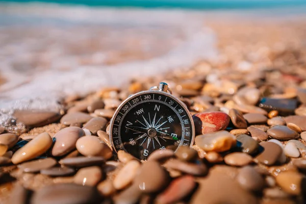 stock image Background image of compass lying on small pebbles of the beach with sea view, travel concept