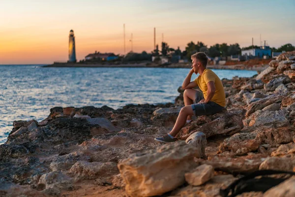 Genç Bir Adam Düşünceli Bir Şekilde Bir Kayanın Üzerinde Oturur — Stok fotoğraf