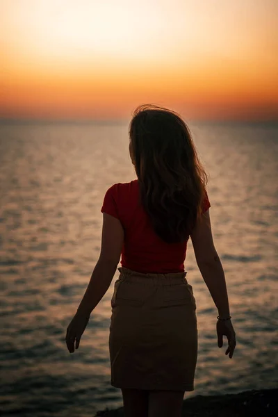 Silhouette of a slender young woman at sunset on the sea
