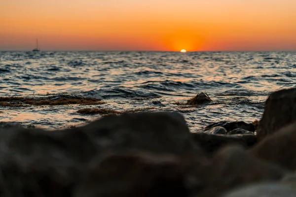 Güneş Gün Batımında Denize Okyanusa Girer Kıyıdaki Kayaların Altından Fotoğraflanır — Stok fotoğraf