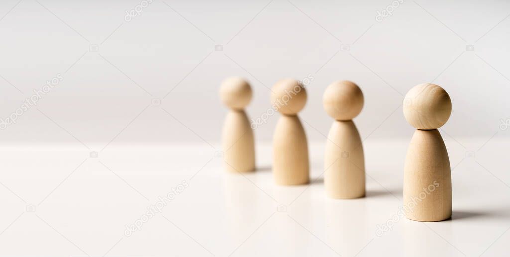Abstract wooden toy figures stand in a row on a white background. Concept of employees in a team, banner