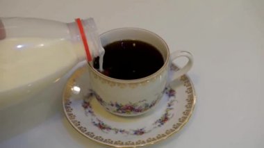 beyaz bir tablo üzerinde beyaz bir fincan kahve için süt ekleme 