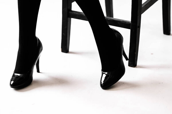 Women's feet in black stockings or tights, black high-heeled shoes