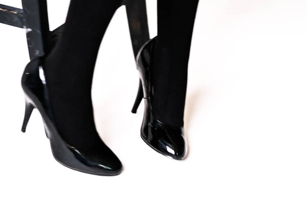 women's feet in black stockings or tights, black high-heeled shoes 