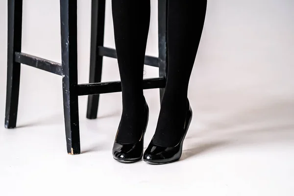 women's feet in black stockings or tights, black high-heeled shoes