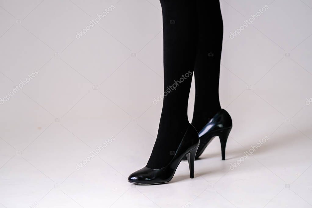 women's feet in black stockings or tights, black high-heeled shoes 