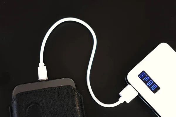 电源银行或电池通过电线与智能手机或平板电脑连接 — 图库照片