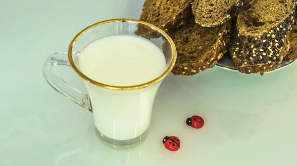 在桌子上的杯子里放牛奶 上面有面包 烘干或苹果 — 图库照片