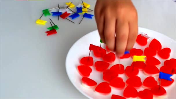 小男孩刺穿糖果的心脏形状与文具按钮明亮的颜色 包括国旗的形式 — 图库视频影像