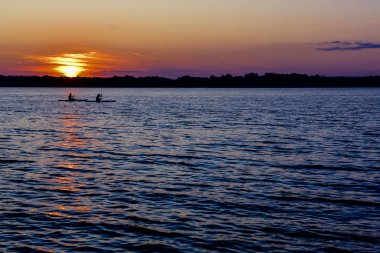 büyük nehirde gün batımı, sakin su üzerinde akşam sörfçü 