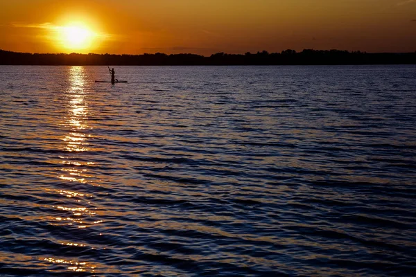 büyük nehirde gün batımı, sakin su üzerinde akşam sörfçü 