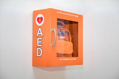 AED turuncu kutusu (Otomatik Dış Defibrilatör) beyaz duvarda tıbbi ilk yardım aygıtı