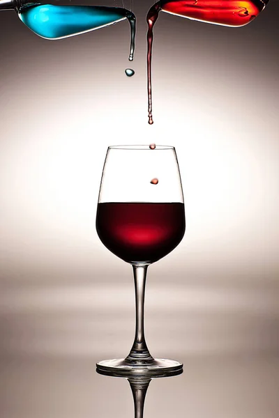 Abstract art of wine glasses, pouring blue and red liquid into wine glass on white background, concept, colorful