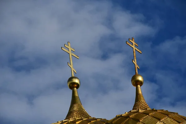 Golden domes with a cross on the background of blue sky and clouds.