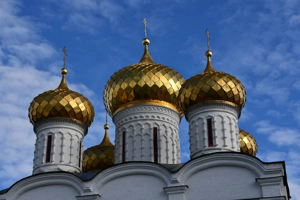 Golden domes with a cross on the background of blue sky and clouds.