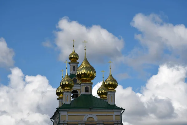Golden domes with a cross on the background of blue sky and clouds.