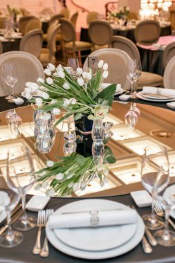 Düğün resepsiyonu için masa hazır. Ayna tavanı yansıtır.