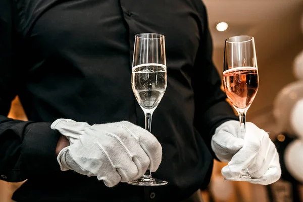 waiter serving champagne. white gloves and a black shirt.