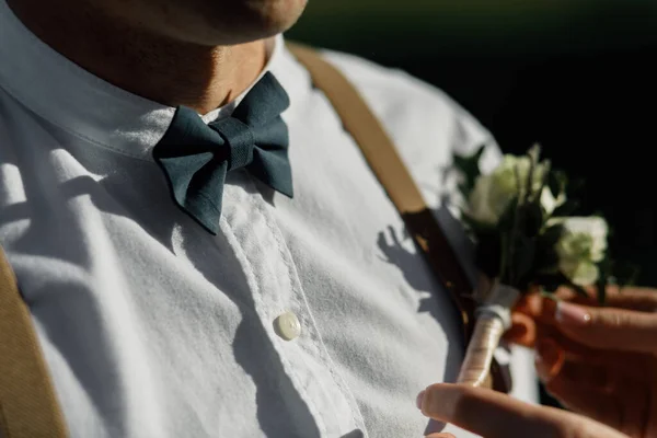 蝶ネクタイとサスペンダー付きの白いシャツの新郎 上品なブートニエール — ストック写真