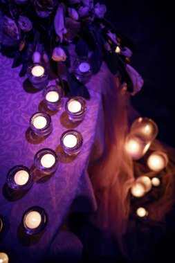 Düğün masası mumlar ve çiçeklerle süslenmiş. karanlık oda mor ışık.