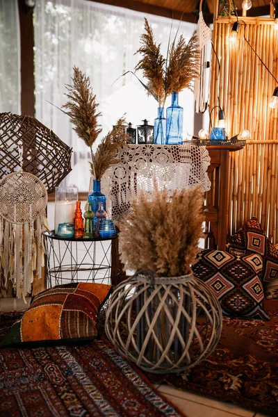 Düğün fotoğraflarının olduğu bölgenin dekorasyonu. Kuru bitkiler ve sazlıklar. Boho tarzı halılar ve vazolar
