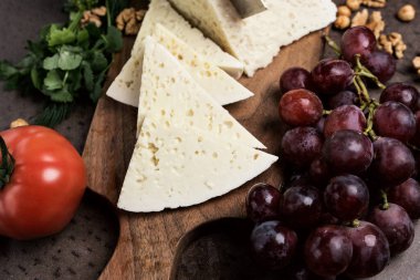 Tahtada üç köşeli peynir dilimleri. Etrafta bir sürü sebze ve üzüm var. Üstten yakından bak. Gürcistan mutfağı