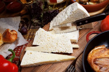 Tahtada üç köşeli peynir dilimleri. Etrafta bir sürü sebze ve üzüm var. Üstten yakından bak. Gürcistan mutfağı