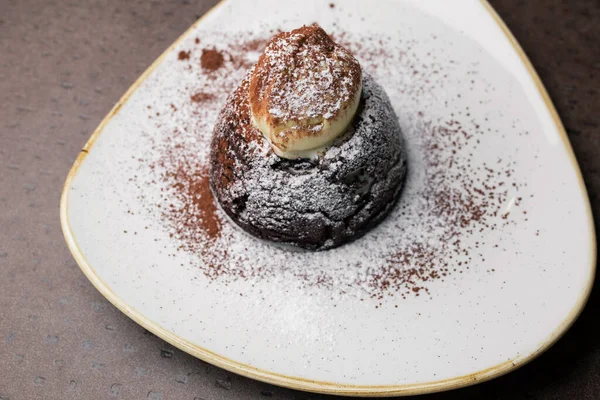 stock image Chocolate cake with white powder on a white plate. dessert close-up, top view