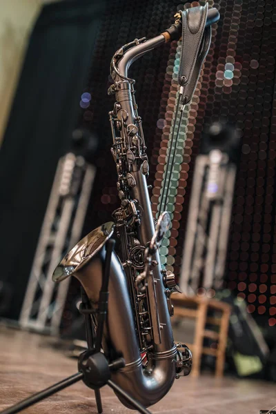 saxophone closeup. the instrument stands on a rack on the stage.