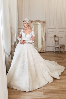 Beyaz elbiseli gelin, fotoğraf stüdyosunda poz veren sarışın kız. Eski tarz iç mimari.