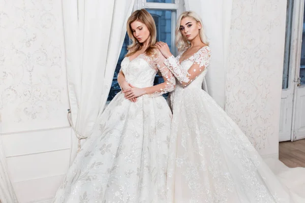Dwie Blondynki Brązowłose Dziewczyny Sukniach Ślubnych Pozują Jasnym Studiu Fotograficznym — Zdjęcie stockowe