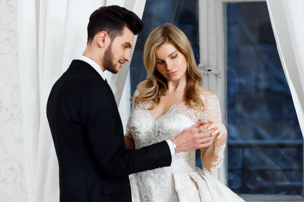  Gelin ve damat bir ışık stüdyosunda antik ayna ve pencerenin yanında duruyorlar..