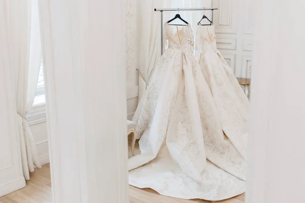 wedding dress on a hanger in a light studio.