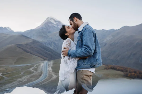 若いグルジアのカップルが山の中でポーズ ジョージアでの結婚式 夕暮れだ ブルージーンズジャケット — ストック写真