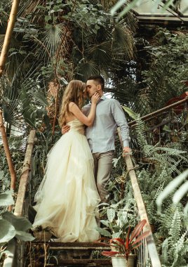 Botanik bahçesinde poz veren genç bir çift. Tropikal bitkilerle düğün fotoğrafı çekimi.