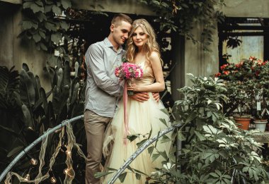 Botanik bahçesinde poz veren genç bir çift. Tropikal bitkilerle düğün fotoğrafı çekimi.