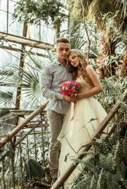 Botanik bahçesinde poz veren genç bir çift. Tropikal bitkilerle düğün fotoğrafı çekimi.