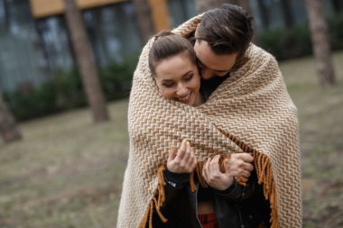 Siyah ceketli genç çift ormanda sarılıp poz veriyor..