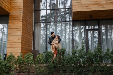 Siyah ceketli genç çift ormanda sarılıp poz veriyor..