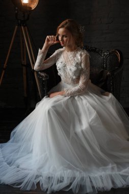 Gelin fotoğraf stüdyosunda poz veriyor. Siyah arkaplan ve klasik lamba