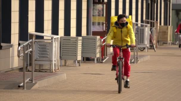 Een fietskoerier levert de bestelling aan de klant binnen covid-19 — Stockvideo