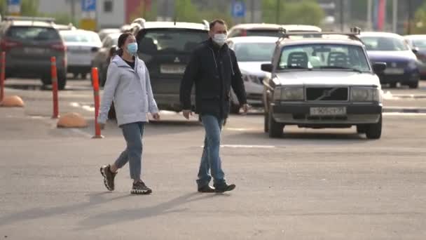 Der Mann und die Frau in Schutzmasken von covid-19 überqueren die Straße — Stockvideo