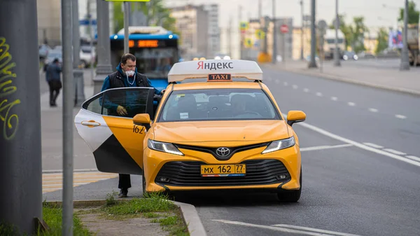 Koronavirüsteki koruyucu tıbbi maskeli bir erkek sarı bir takside oturuyor. - Stok İmaj